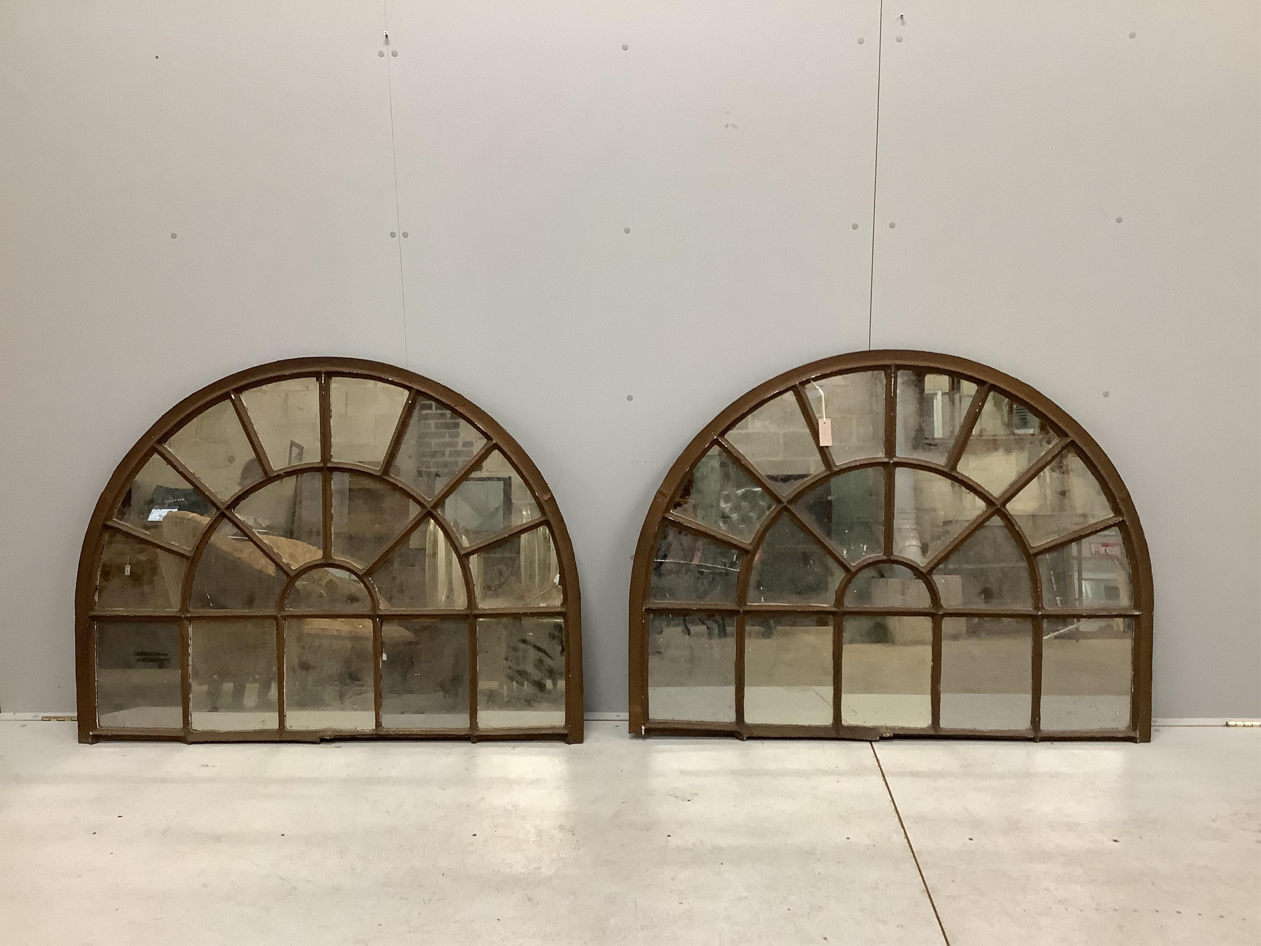 A pair of architectural cast iron window panel wall mirrors of domed form, width 136cm, height 102cm. Condition - fair, four panes cracked.